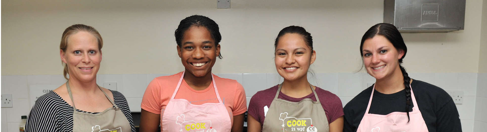Four women in aprons smiling