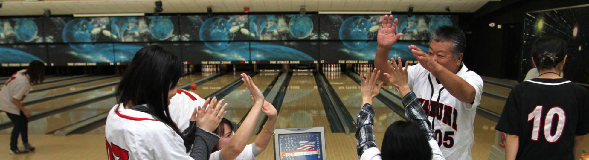 A family of 4 giving each other high 5 at Bowling center