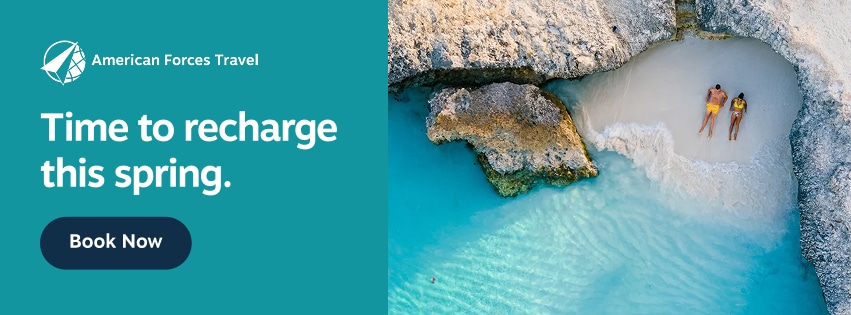amercian forces travel spring campaign 851 x 315 Promotional graphic for American Forces Travel showing a small sandy beach cove with turquoise water, rocky cliffs, and two people lying on the sand. Text on the graphic reads “American Forces Travel. Time to recharge this spring. Book Now.”